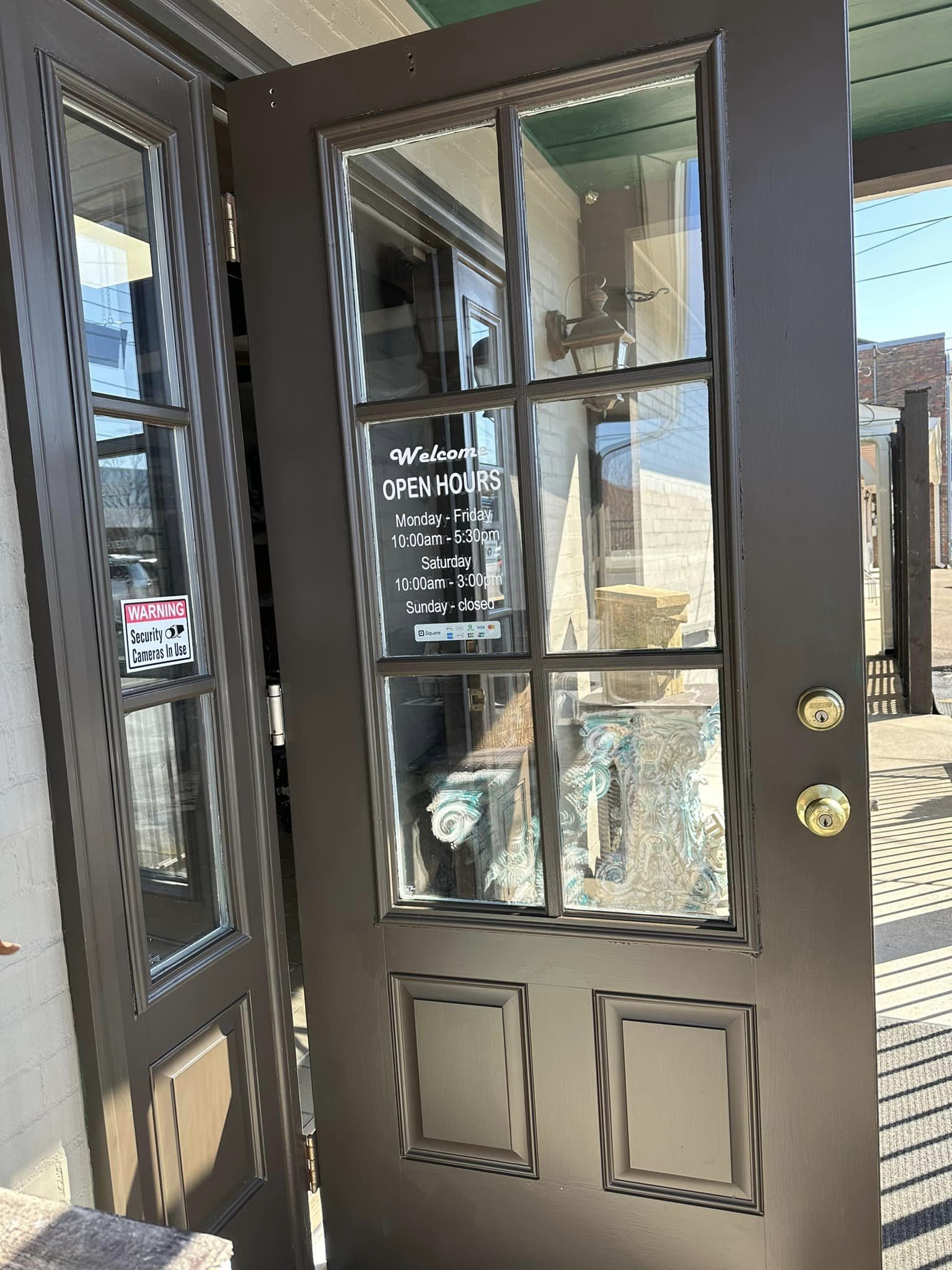 Brown door with glass panels and open hours sign, reflecting a building interior.
