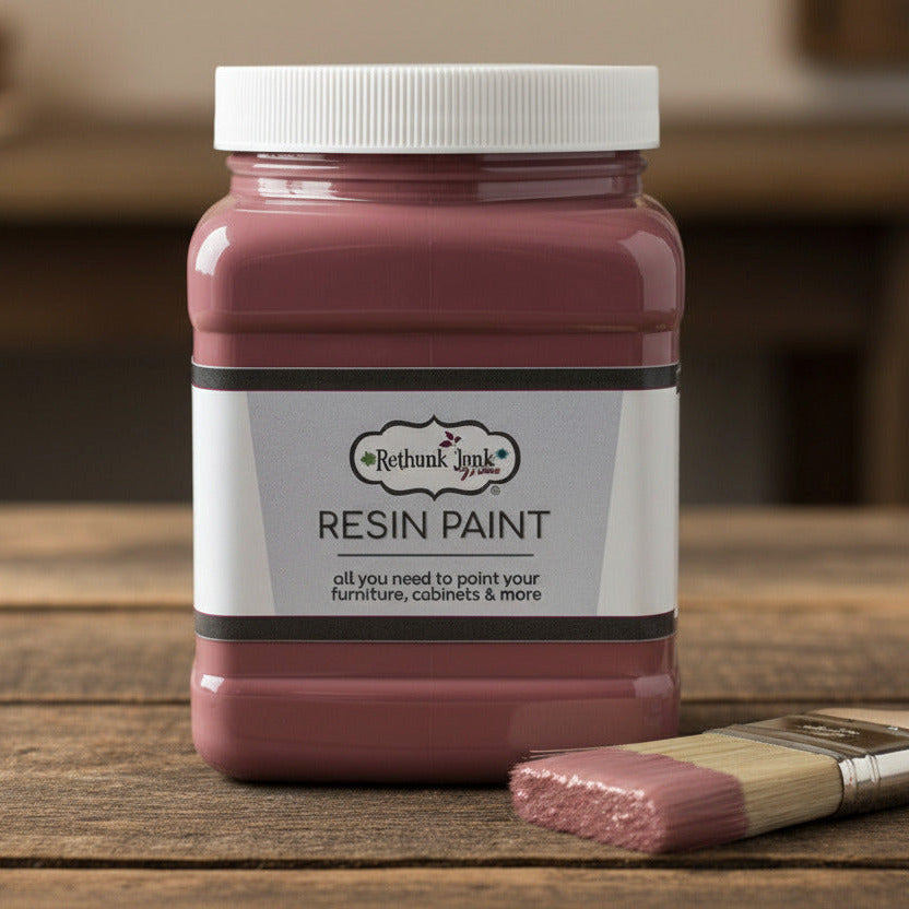 Jar of resin paint with a white lid on a table with a paint brush beside it